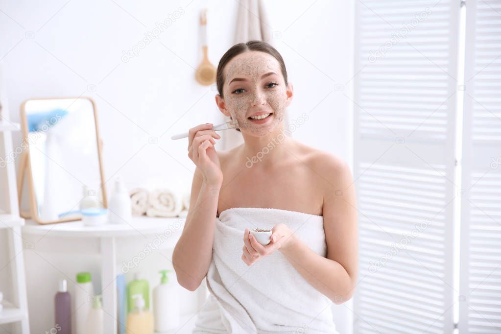 Woman applying scrub onto face in bathroom