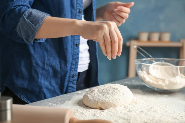 Mujer rociando la harina sobre la masa en la mesa en la cocina —  Fotos de Stock