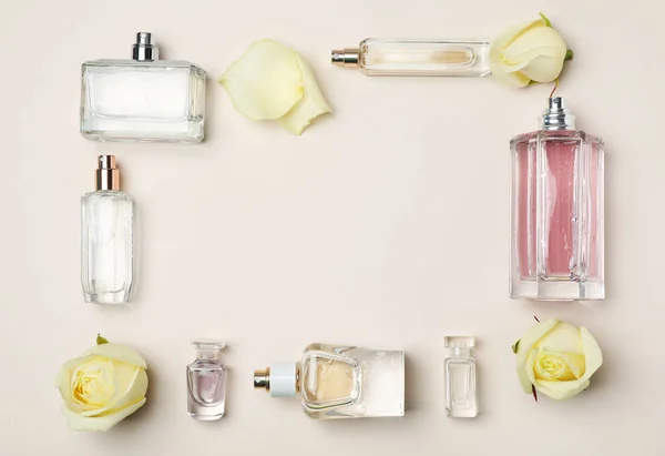 Flache Lagekomposition mit Flaschen Parfüm und Rosen auf hellem Hintergrund — Stockfoto