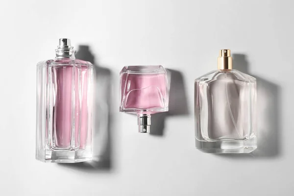 Bottles of perfume on light background, top view — Stock Photo, Image