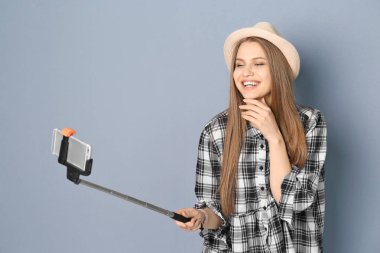 Selfie gri bir arka plana dayanır alarak genç güzel kadın