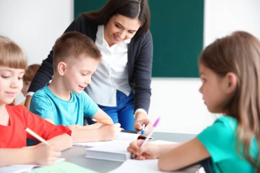 Kadın öğretmen çocuk okulda sınıfta onun görevi ile yardım