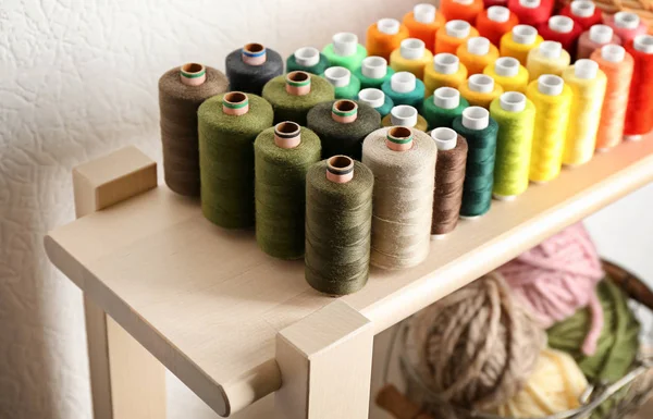 Juego de hilos de costura de color en estante de madera — Foto de Stock