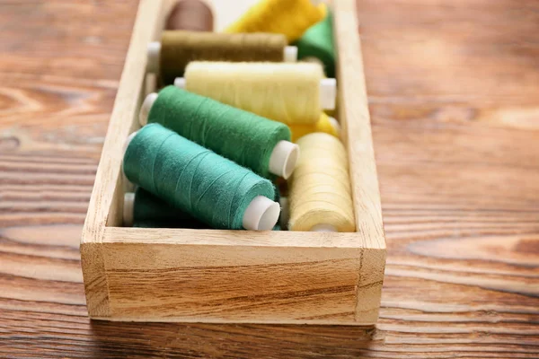 Contenedor con juego de hilos de costura de color sobre fondo de madera —  Fotos de Stock