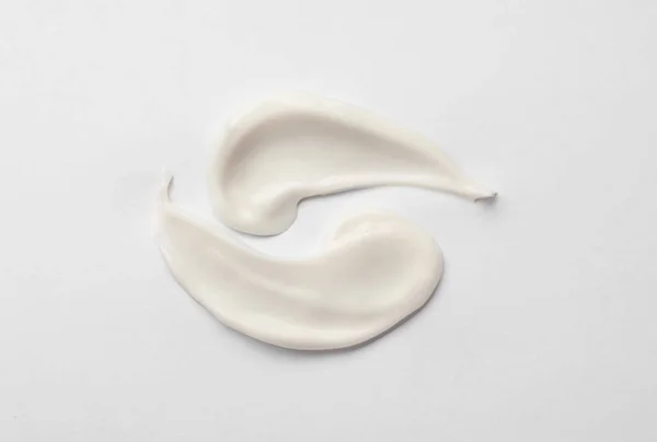 Crème uitstrijkjes op witte achtergrond. Cosmetisch product — Stockfoto