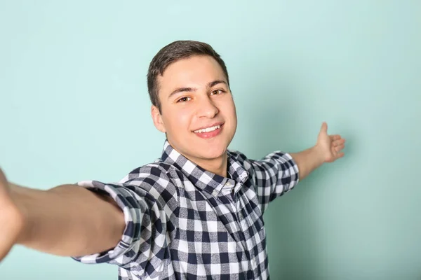 Fiatal jóképű férfi, figyelembe véve a selfie színes háttérrel — Stock Fotó