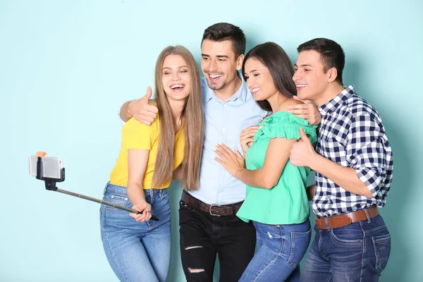 Jóvenes amigos felices tomando selfie contra el fondo de color — Foto de Stock