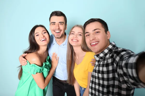 Jóvenes amigos felices tomando selfie contra el fondo de color —  Fotos de Stock