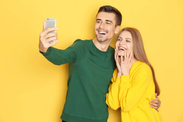 Jovem lindo casal tomando selfie contra fundo de cor — Fotografia de Stock