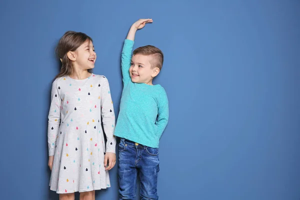 Küçük kız ve erkek renk arka plan üzerinde kendi yükseklik ölçme — Stok fotoğraf