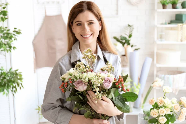 Female florist with beautiful bouquet at workplace