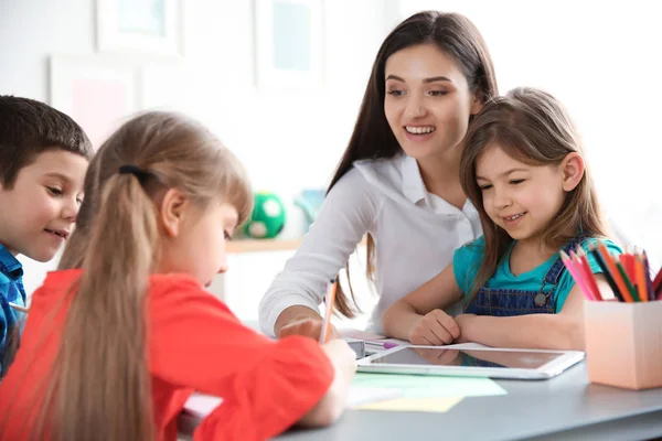 Vrouwelijke leraar meisje helpen met haar taak in klas op school — Stockfoto