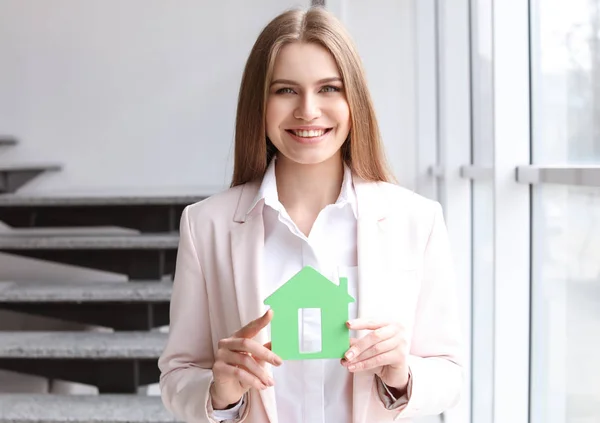 Mooie onroerende goederenagent met huis model binnenshuis — Stockfoto