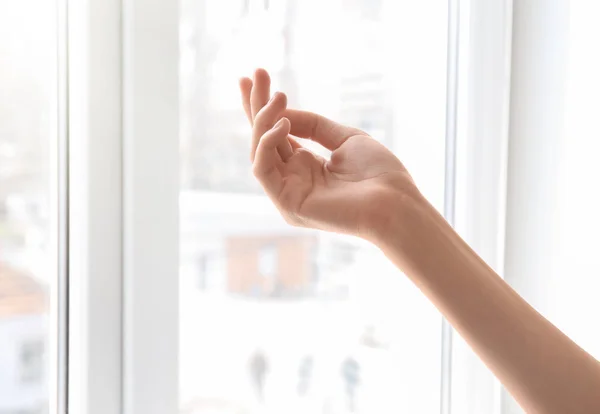 Молодая женщина у окна. Сосредоточься на руке, увлажненной кремом — стоковое фото