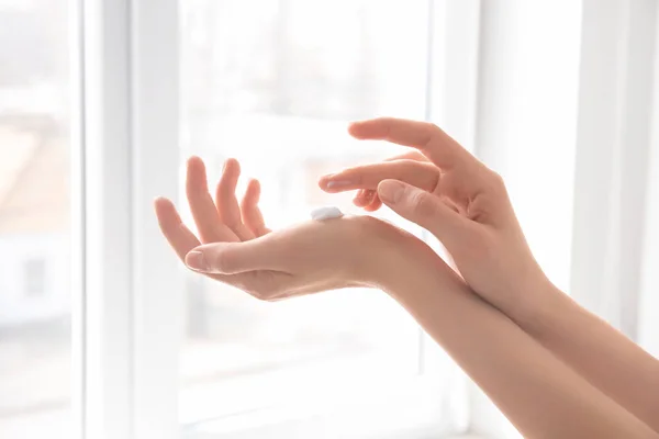 Молодая женщина наносит крем для рук на окно — стоковое фото