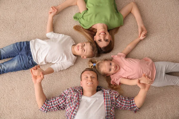 Happy family lying on cozy carpet at home, top view — Stock Photo, Image