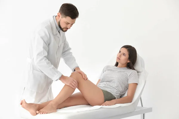 Doctor examining female patient with injured leg in clinic — Stock Photo, Image