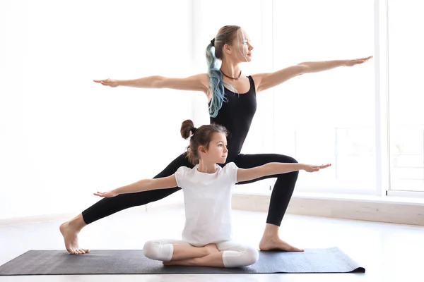 Маленькая девочка и ее учитель практикуют йогу в спортзале — стоковое фото