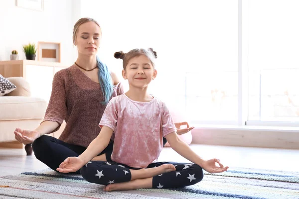 Junge Mutter und ihre Tochter praktizieren Yoga zu Hause — Stockfoto