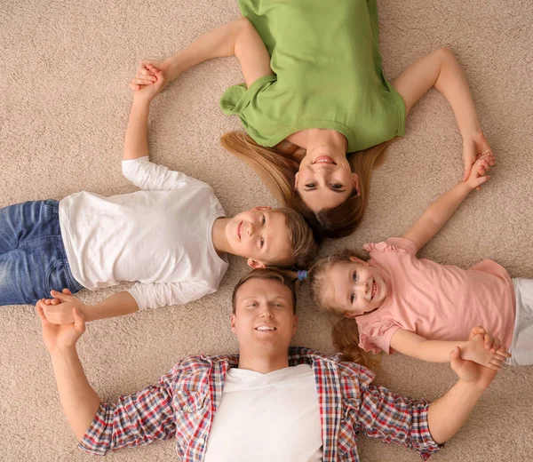 Happy family lying on cozy carpet at home, top view — Stock Photo, Image
