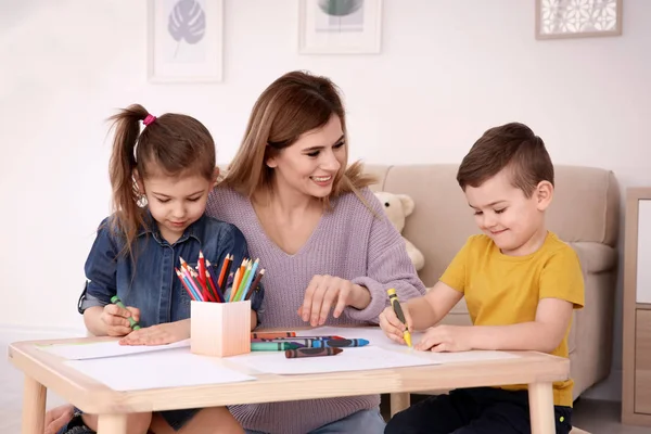 Lindos niños pequeños y su niñera dibujo en casa —  Fotos de Stock