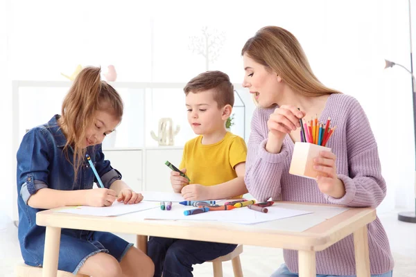 Roztomilé malé děti a jejich chůva kreslení doma — Stock fotografie