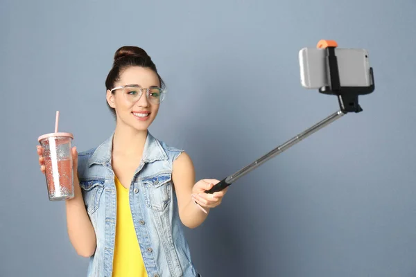 Junge schöne Frau macht Selfie vor grauem Hintergrund — Stockfoto