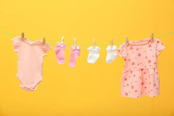 Roupas infantis na linha de lavanderia contra fundo de cor — Fotografia de Stock