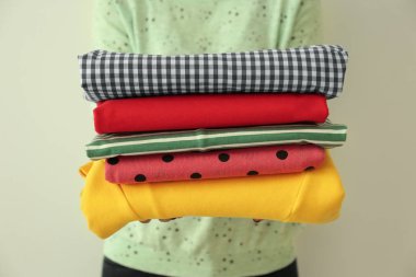 Temiz elbise yığını üzerinde açık renkli tutan kadın