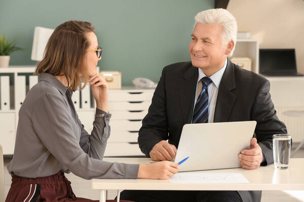 Зрелый мужчина консультируется с женщиной в офисе
