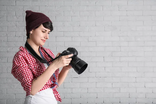 Joven fotógrafa con cámara sobre fondo de ladrillo — Foto de Stock