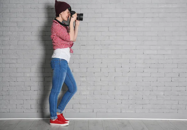 Νεαρή γυναίκα φωτογράφος με την μηχανή κοντά σε τοίχο από τούβλα — Φωτογραφία Αρχείου