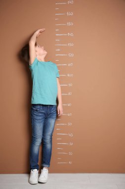 Küçük çocuk renk duvarının yakınında onun yükseklik ölçme
