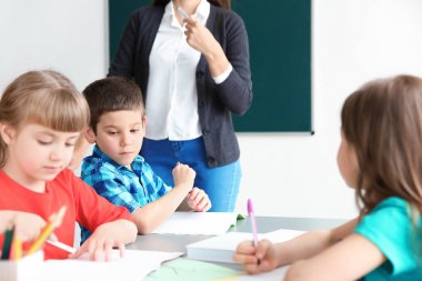 Kadın öğretmen çocuk okulda sınıfta onun görevi ile yardım