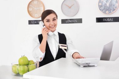 Kadın resepsiyonist otel işyerinde telefonda konuşuyor