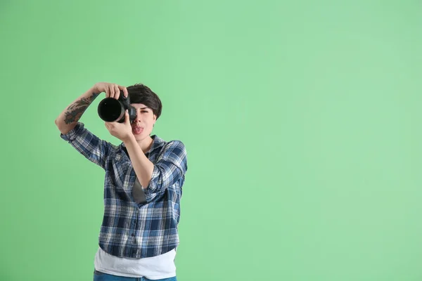 Young female photographer with camera on color background — Stock Photo, Image