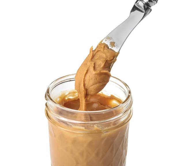 Glas und Messer mit cremiger Erdnussbutter auf weißem Hintergrund — Stockfoto