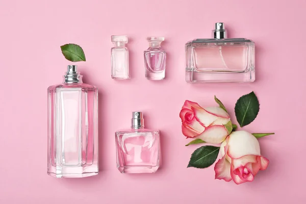 Flaschen Parfüm und Rosen auf farbigem Hintergrund, Draufsicht — Stockfoto