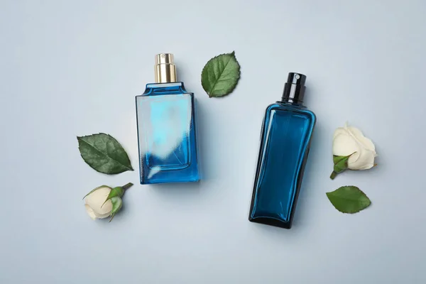 Butelek perfum i róż na jasnym tle, widok z góry — Zdjęcie stockowe