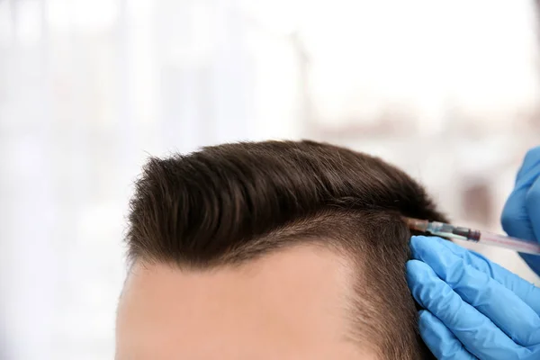 Jovem com problema de perda de cabelo recebendo injeção em fundo borrado, close-up — Fotografia de Stock