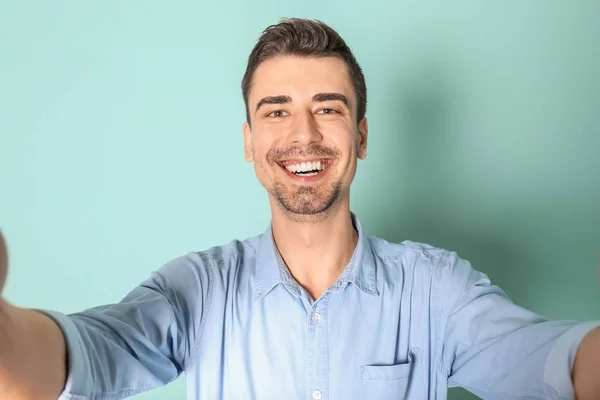 Jeune bel homme prenant selfie sur fond de couleur — Photo