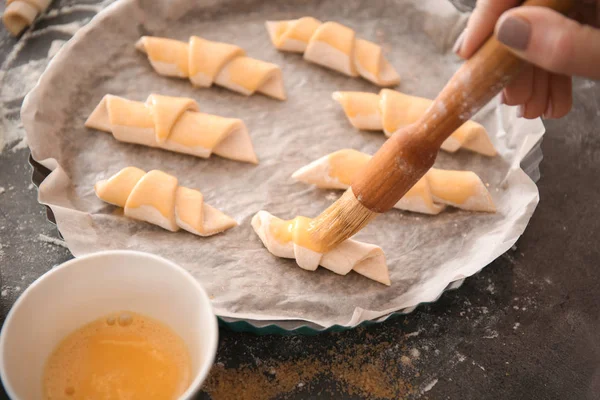 Mulher espalhando gema de ovo em croissants, close-up — Fotografia de Stock