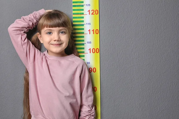 Niña Midiendo Altura Sobre Fondo Gris —  Fotos de Stock