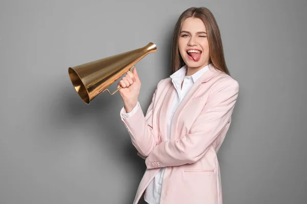 Jovem mulher com megafone em fundo cinza — Fotografia de Stock