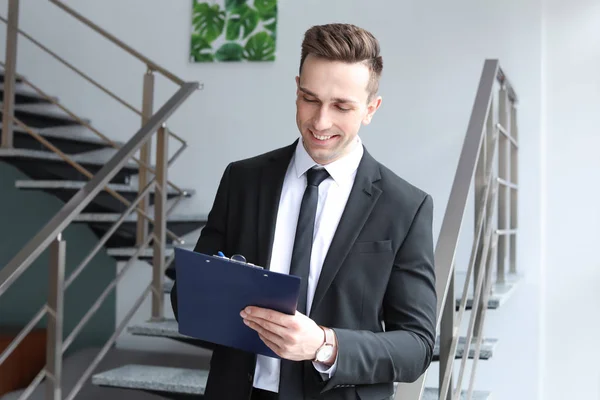 Männlicher Immobilienmakler mit Klemmbrett drinnen — Stockfoto