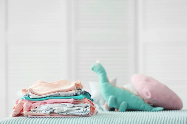 ベッドの上の赤ちゃんの服の山 — ストック写真