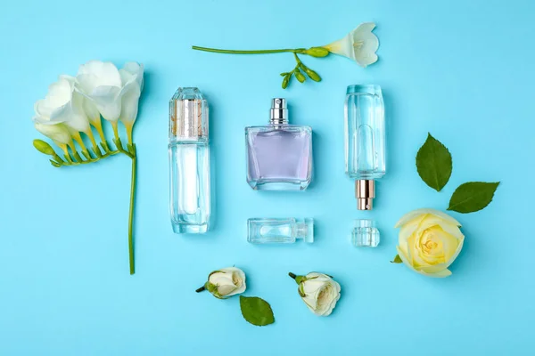 Flaschen Parfüm und Blumen auf farbigem Hintergrund, Draufsicht — Stockfoto
