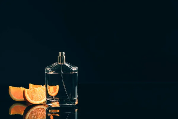 香水瓶と黒の背景に柑橘系の果物のスライス — ストック写真