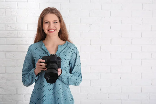 Vrouwelijke fotograaf met de camera op baksteen achtergrond — Stockfoto