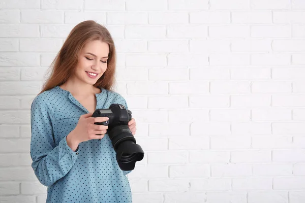 Fotógrafo feminino com câmera no fundo de tijolo — Fotografia de Stock